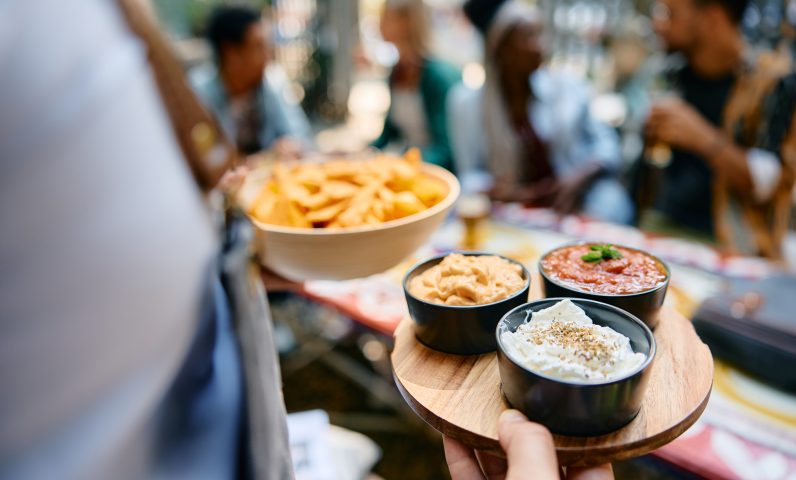 Close up of waiter serving food while working in a restaurant.