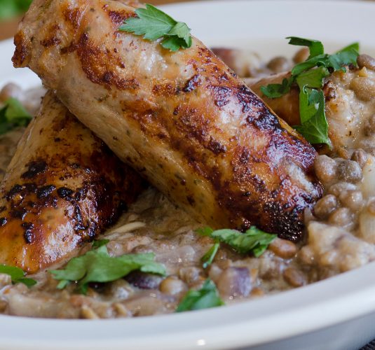 Pork sausages with creamy lentils and parsley in a bowl
