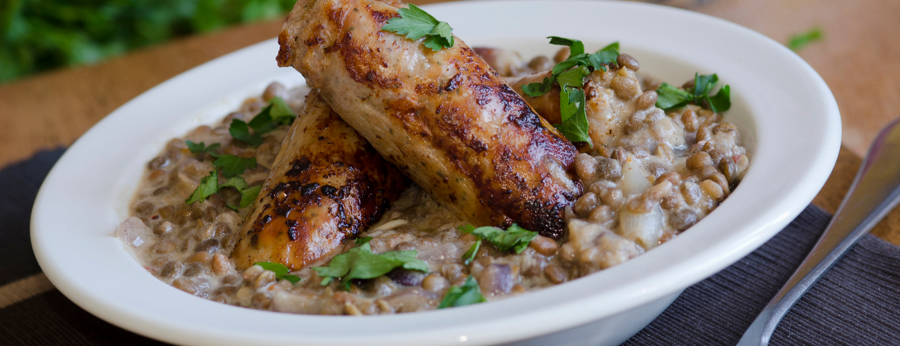 Pork sausages with creamy lentils and parsley in a bowl