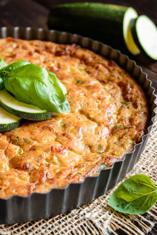 Zucchini pie with bacon, cheese, onion, parsley and basil