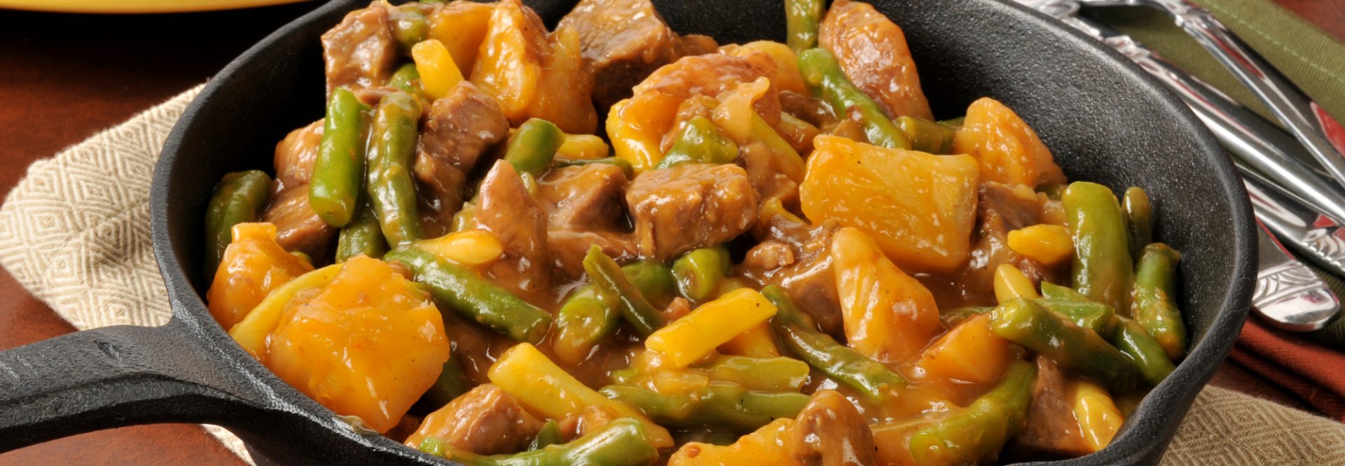 A skillet dinner with braised beef, potatoes and beans