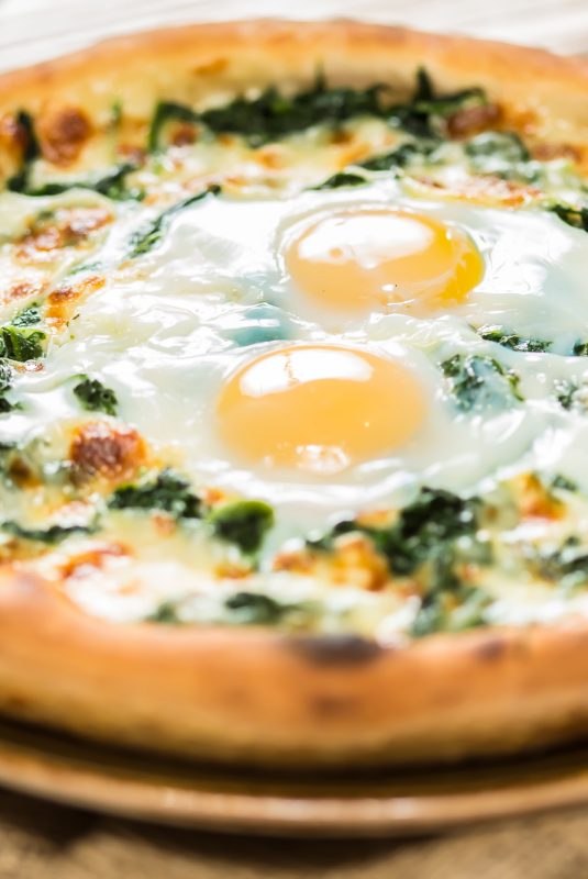 Margarita pizza with arugula and egg for breakfast, selective focus