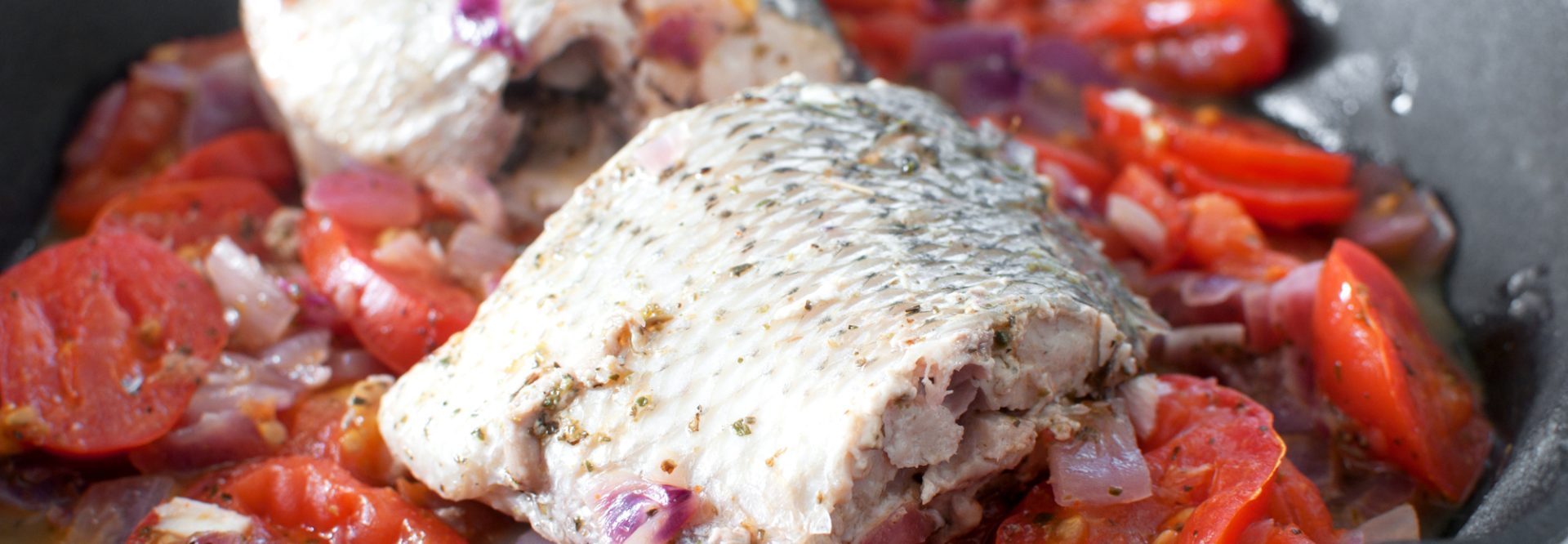 Sauteed bass fish pieces with tomatoes and onion