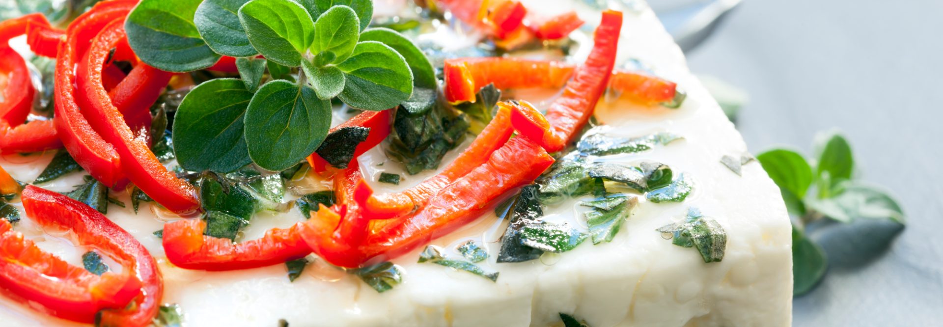 Baked feta cheese with oregano and chilli.  On dark slate.