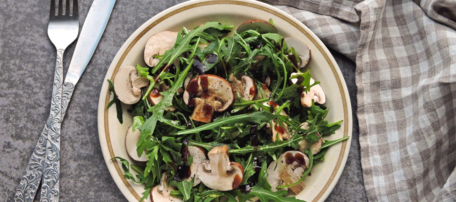 Healthy salad with arugula and raw champignons.